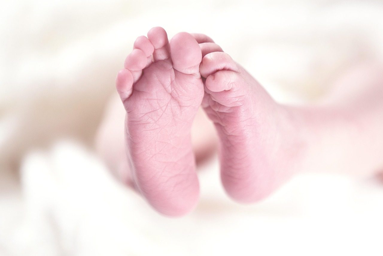 A pair of baby feet on a white blanket.