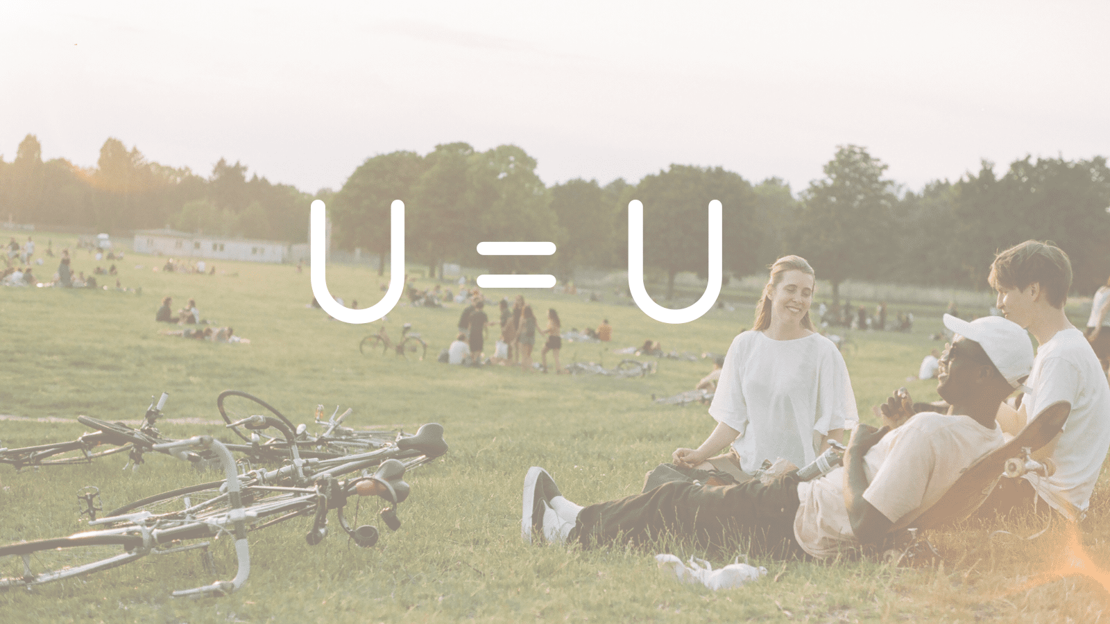 A semi-transpparent photograph of people hanging out in a sunny park. Super imposed over it is text reading "U=U"